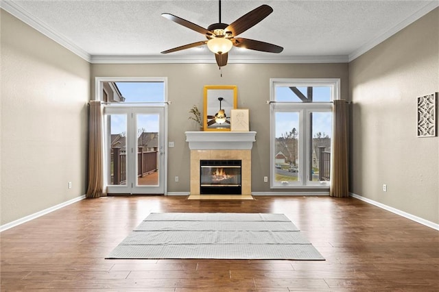 unfurnished living room with a tile fireplace, hardwood / wood-style flooring, ceiling fan, crown molding, and a textured ceiling