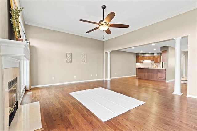 unfurnished living room featuring ornate columns, wood-type flooring, crown molding, ceiling fan, and a premium fireplace