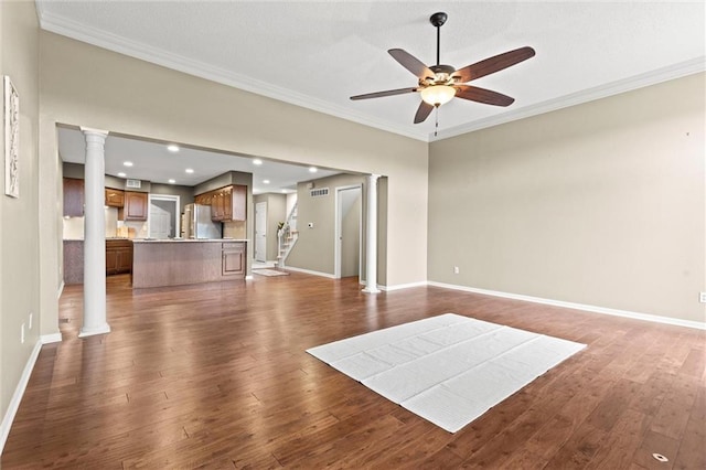 unfurnished living room with ornate columns, crown molding, dark wood-type flooring, and ceiling fan