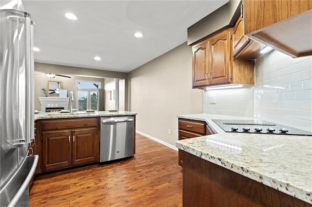 kitchen with appliances with stainless steel finishes, ventilation hood, sink, decorative backsplash, and dark wood-type flooring