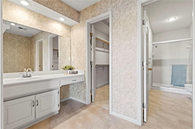 bathroom featuring vanity, a textured ceiling, tile patterned floors, toilet, and walk in shower