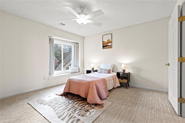 bedroom with ceiling fan, light colored carpet, and a textured ceiling