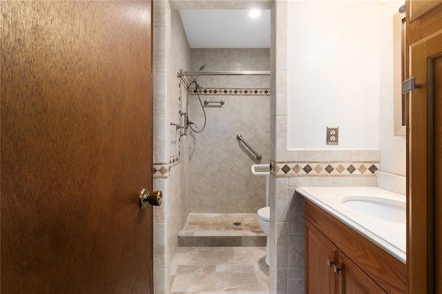 bathroom with vanity, a tile shower, tile walls, and toilet