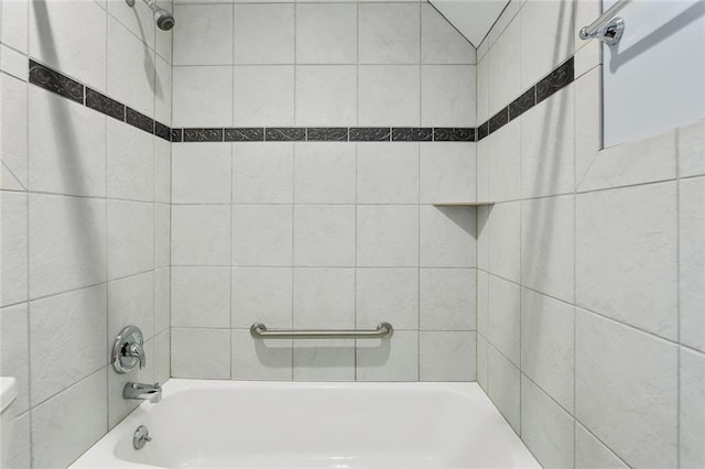 bathroom with toilet and tiled shower / bath