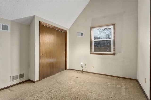 unfurnished bedroom featuring vaulted ceiling, carpet flooring, a textured ceiling, and a closet