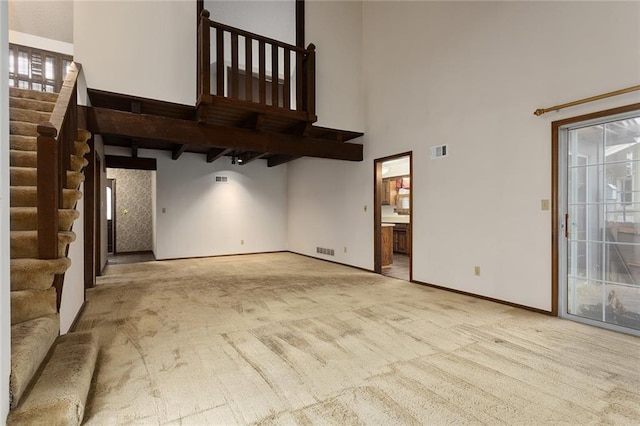 unfurnished living room with a towering ceiling and light colored carpet