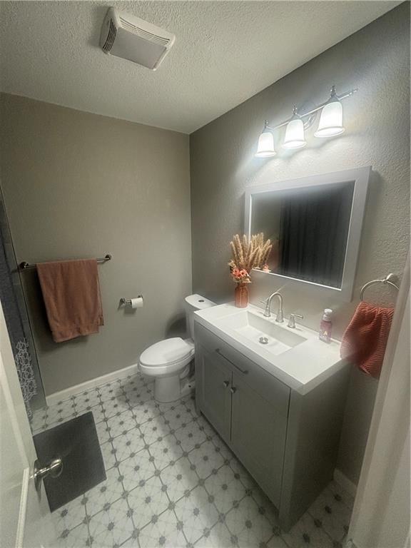 bathroom with vanity, a textured ceiling, and toilet