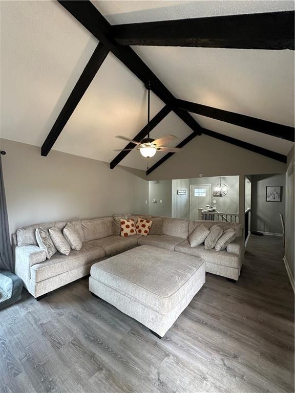 unfurnished living room featuring lofted ceiling with beams, ceiling fan, and dark hardwood / wood-style flooring