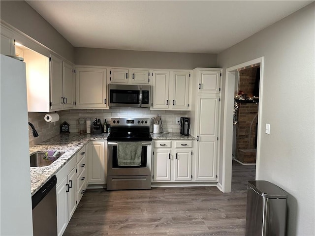 kitchen featuring appliances with stainless steel finishes, light stone countertops, sink, and white cabinets