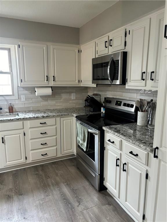 kitchen with white cabinetry, stainless steel appliances, dark hardwood / wood-style floors, and tasteful backsplash