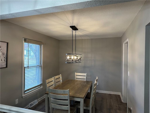 dining area with dark hardwood / wood-style flooring, a chandelier, and a textured ceiling