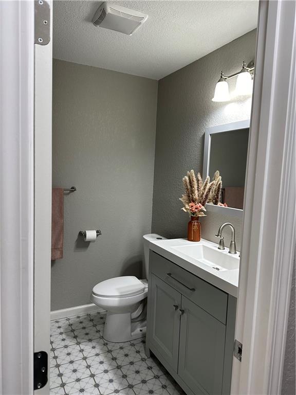 bathroom with vanity, a textured ceiling, and toilet