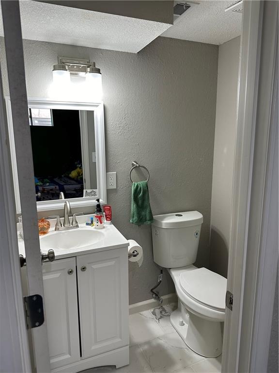 bathroom featuring vanity, a textured ceiling, and toilet