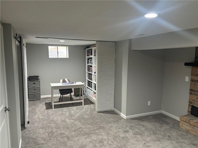 basement featuring a barn door, a fireplace, and carpet