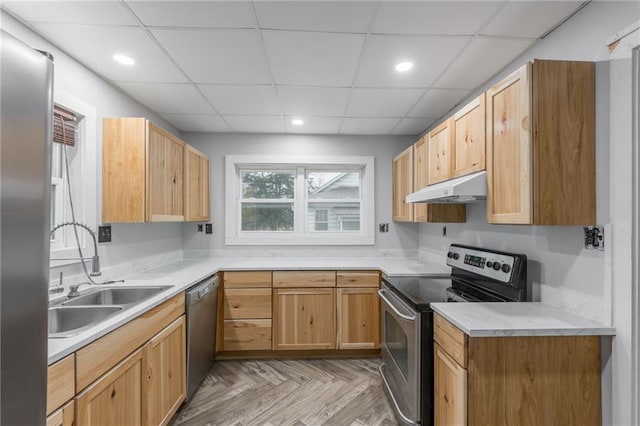 kitchen with a drop ceiling, light brown cabinets, light parquet floors, sink, and appliances with stainless steel finishes