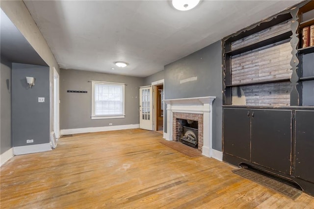 unfurnished living room with light hardwood / wood-style floors and a brick fireplace