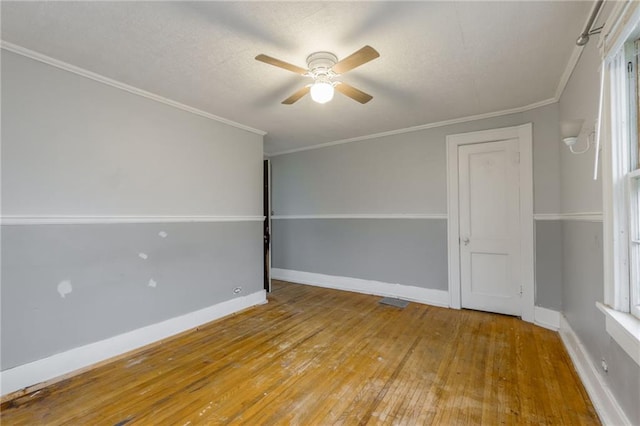 spare room featuring ceiling fan, plenty of natural light, light wood-type flooring, and ornamental molding