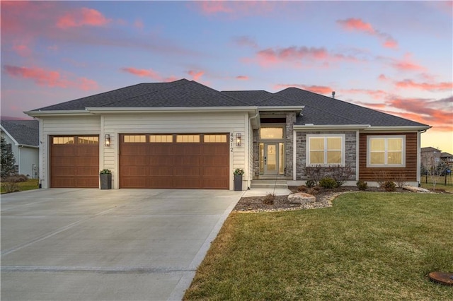 prairie-style home featuring a garage and a yard