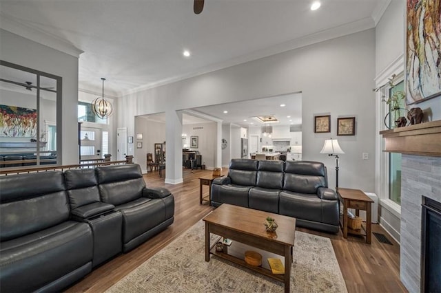 living room featuring ornamental molding, wood-type flooring, and ceiling fan with notable chandelier