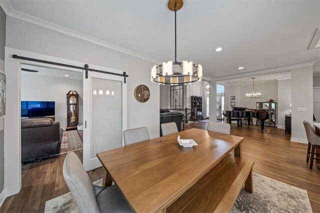 dining area featuring a notable chandelier, crown molding, a barn door, and hardwood / wood-style flooring