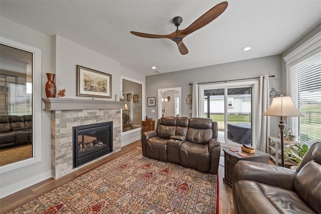 living room featuring wood-type flooring, ceiling fan, and a fireplace