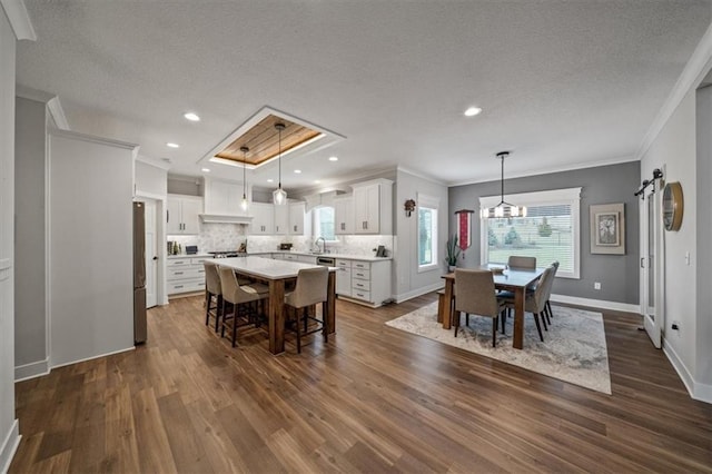 dining space with dark hardwood / wood-style flooring, sink, crown molding, and a barn door