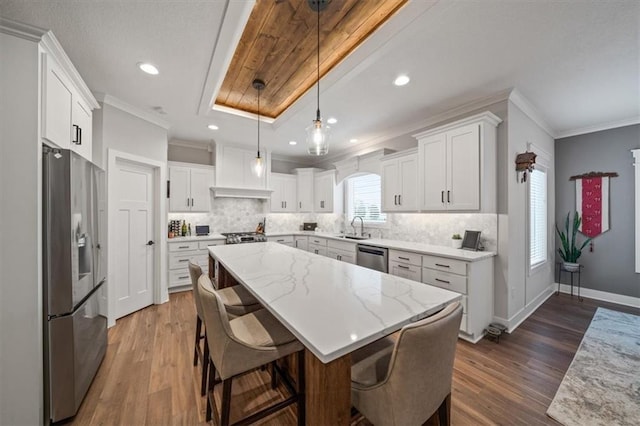 kitchen featuring stainless steel appliances, white cabinetry, a center island, and pendant lighting