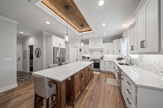 kitchen featuring sink, appliances with stainless steel finishes, custom range hood, white cabinets, and a kitchen island