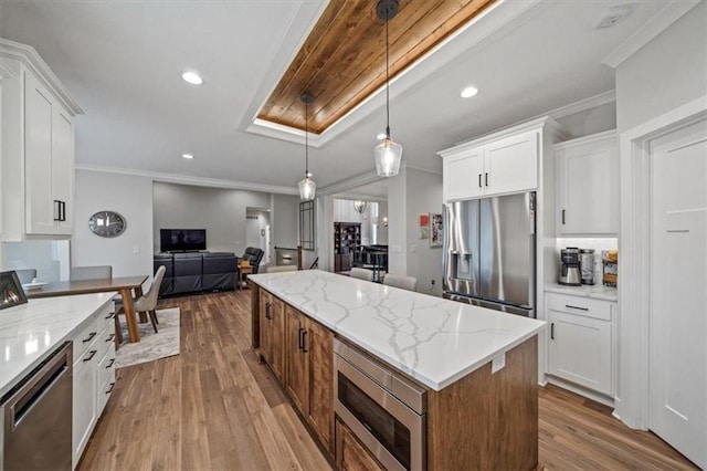 kitchen with white cabinetry, hanging light fixtures, light stone counters, and stainless steel appliances