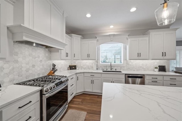 kitchen with appliances with stainless steel finishes, sink, white cabinets, hanging light fixtures, and a healthy amount of sunlight