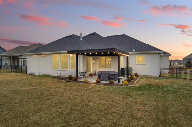 back house at dusk with a yard and a patio area