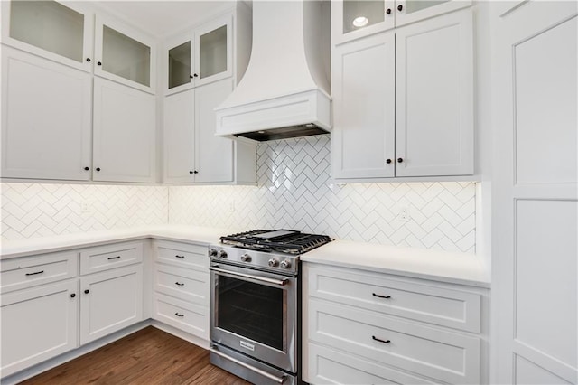 kitchen with premium range hood, dark hardwood / wood-style floors, white cabinets, backsplash, and stainless steel range