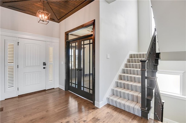 foyer with an inviting chandelier, hardwood / wood-style floors, wooden ceiling, and french doors