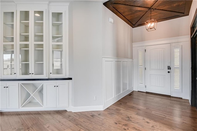 foyer entrance with an inviting chandelier, light hardwood / wood-style floors, and wooden ceiling