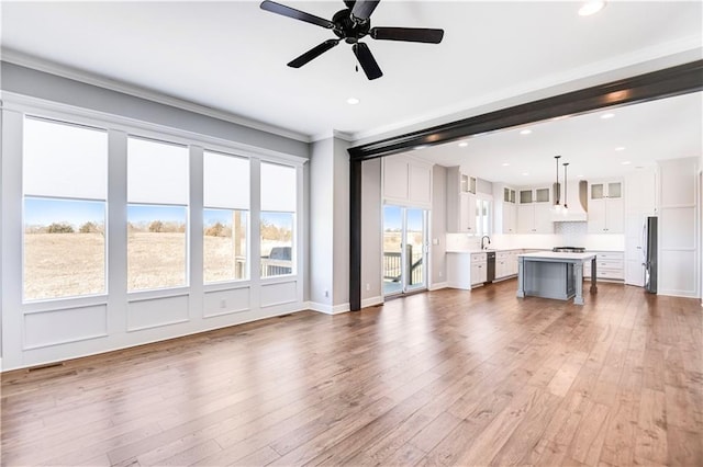 unfurnished living room with crown molding, dark hardwood / wood-style floors, sink, and ceiling fan