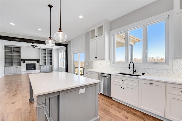 kitchen with sink, white cabinetry, stainless steel dishwasher, a kitchen island, and pendant lighting