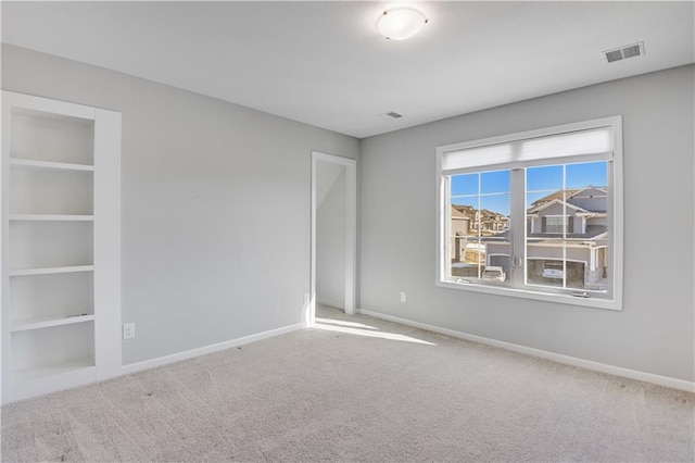 unfurnished room featuring built in shelves and carpet flooring