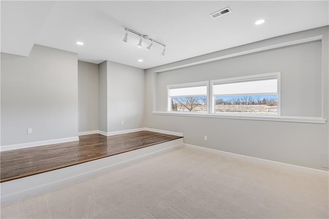 spare room with rail lighting and carpet