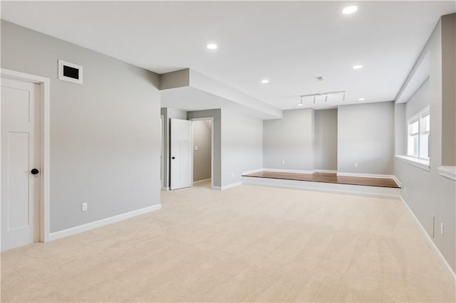 unfurnished room featuring track lighting and light colored carpet