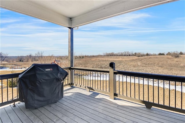 wooden deck with a rural view and grilling area