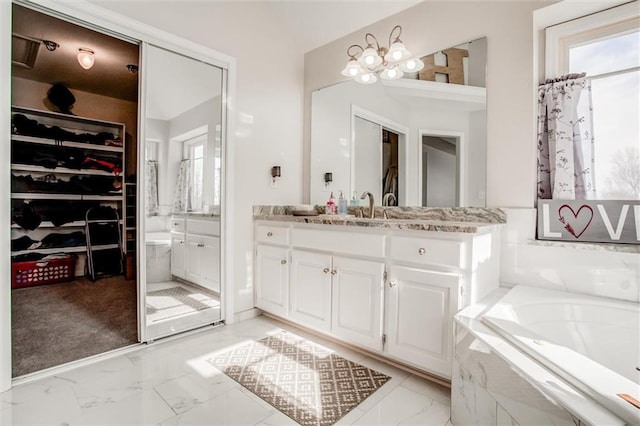 bathroom featuring a relaxing tiled tub and vanity