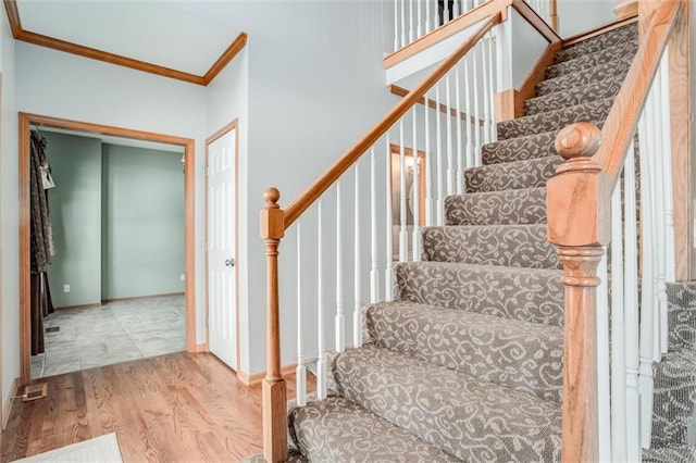 stairway with hardwood / wood-style floors and crown molding