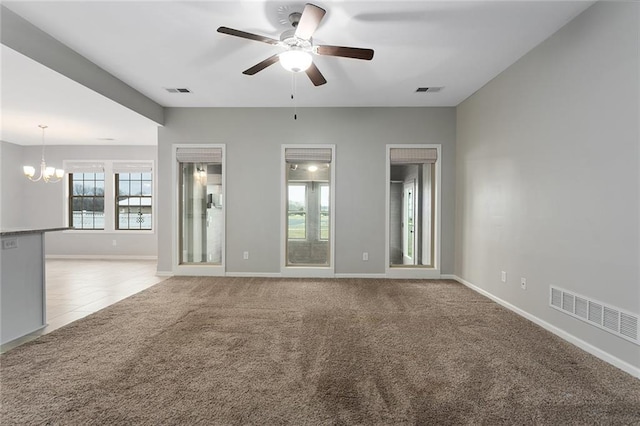 carpeted spare room with ceiling fan with notable chandelier