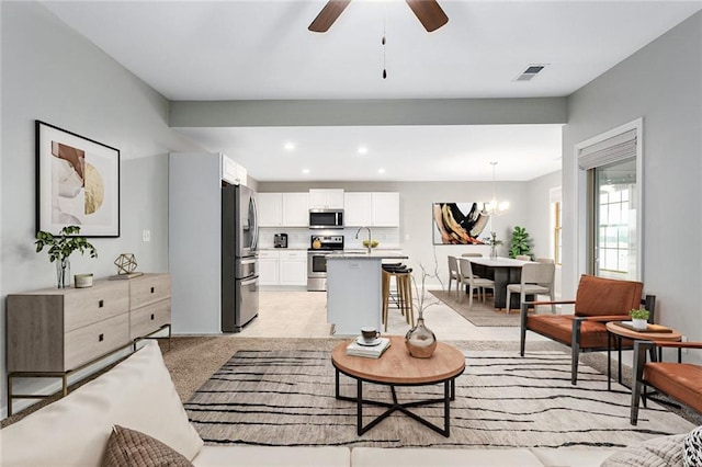 carpeted living room with ceiling fan with notable chandelier and sink