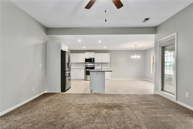 kitchen with decorative light fixtures, stainless steel appliances, white cabinetry, a sink, and light carpet