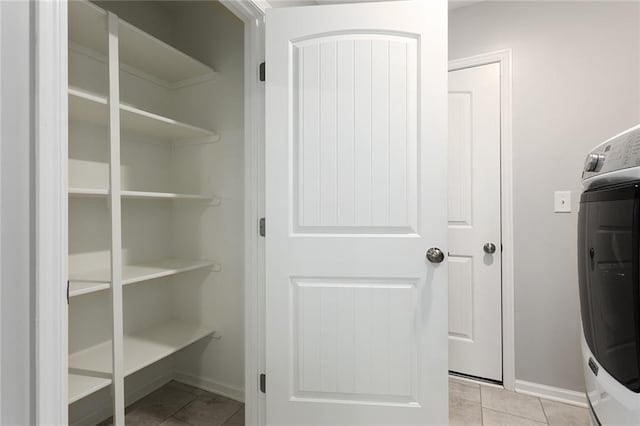 laundry room featuring washer / clothes dryer, laundry area, light tile patterned flooring, and baseboards