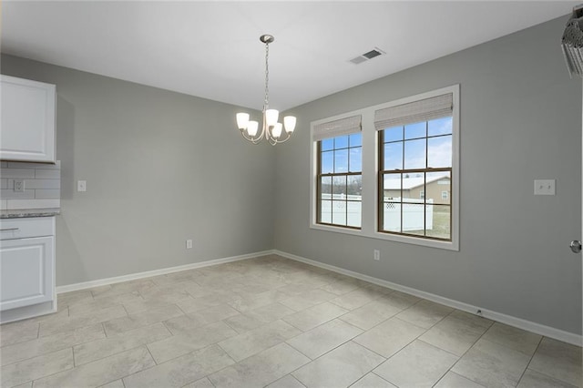 unfurnished dining area with an inviting chandelier, baseboards, and visible vents