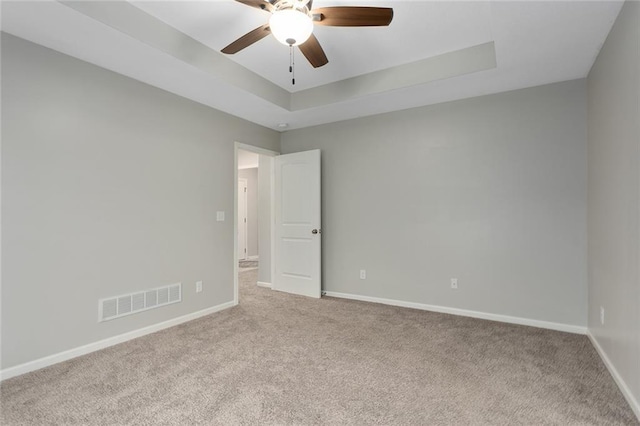 unfurnished room featuring light carpet, baseboards, visible vents, ceiling fan, and a tray ceiling