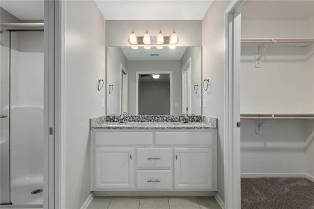 bathroom with a sink, a spacious closet, a shower stall, and double vanity