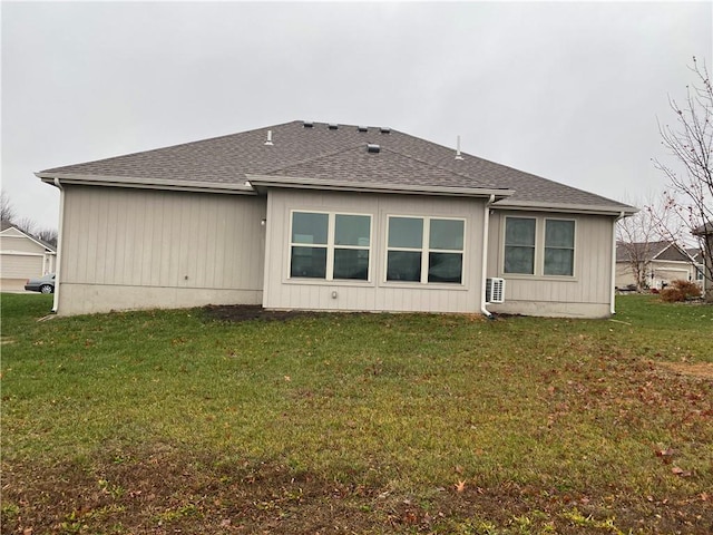 back of property featuring a yard and roof with shingles